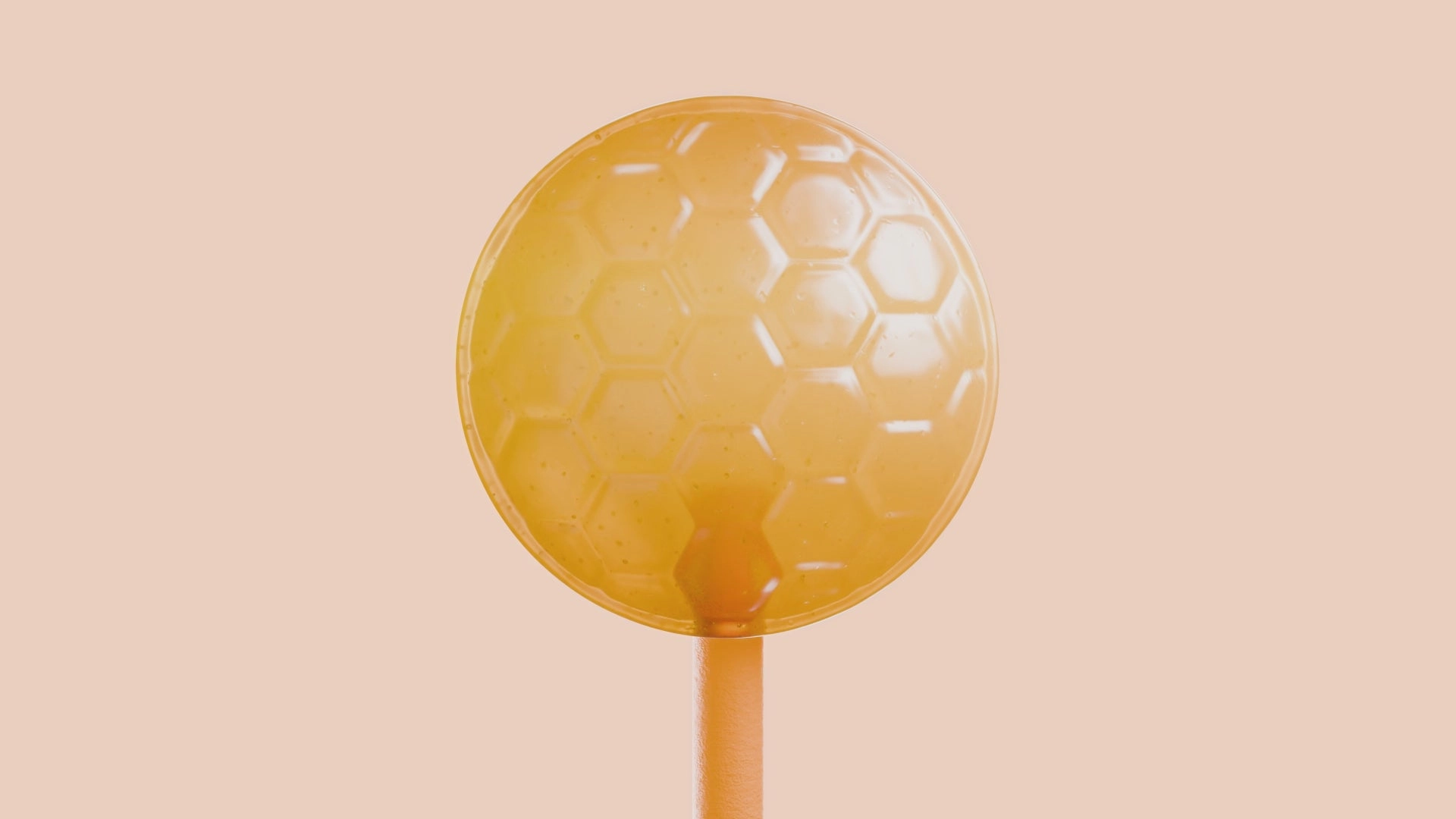 A honey-colored lollipop on a stick against a peach backdrop