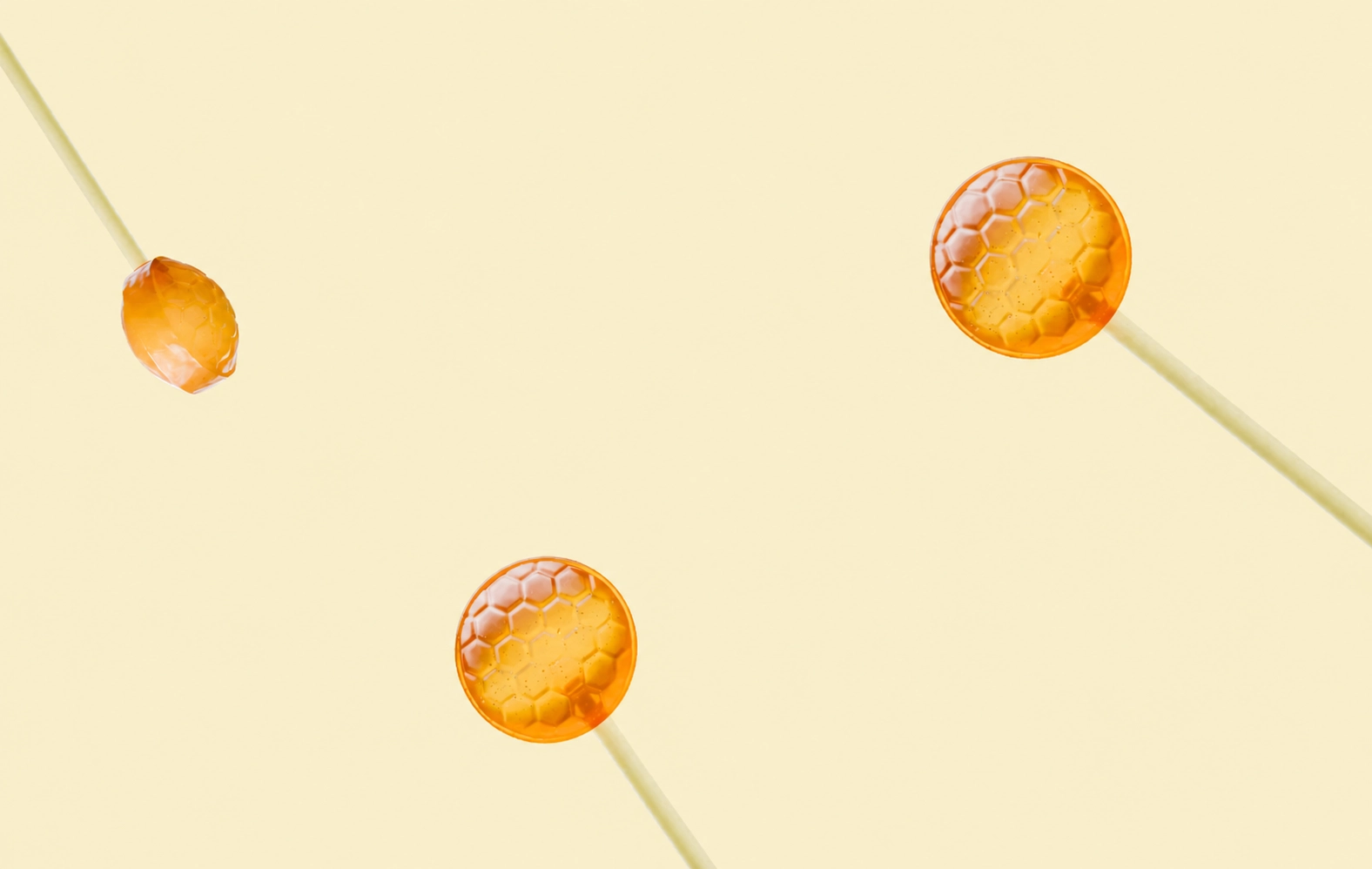 Three honey lollipops floating on a cream backdrop
